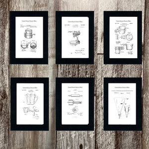 A set of framed baking patent art prints displayed on a wooden surface. The patents are for various baking tools and appliances.
