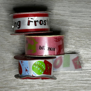 Three spools of ribbon with festive designs on a textured surface